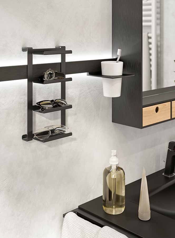 Neben einem Waschbecken im Badezimmer hängt eine Ablage mit Brillen und einer Uhr