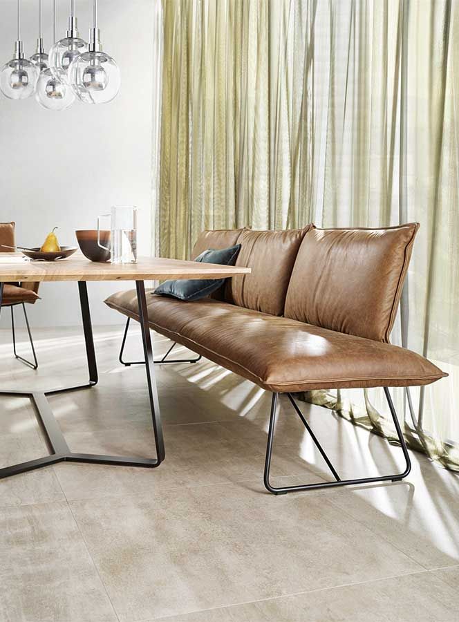 Heller Holztisch an dem eine Ledersitzbank und Lederstühle stehen