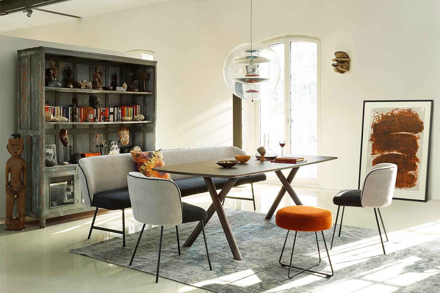 Esszimmer mit einem Holztisch einer graublauen Sitzbank sowie Stühlen und einem offenen Vintageschrank 