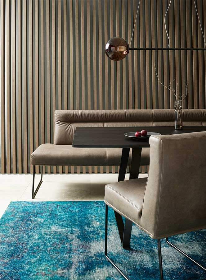 Esstisch 6 Schwarzer Tisch an dem eine Lederbank und ein Ledersuhl stehen auf einem petrolfarbenden Teppich