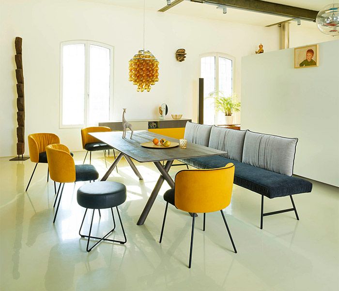 Esszimmer Mood 2 Esszimmertisch mit gelb-blauen Stühelen und einer gelb-blauen Sitzbank in einem hellen Raum