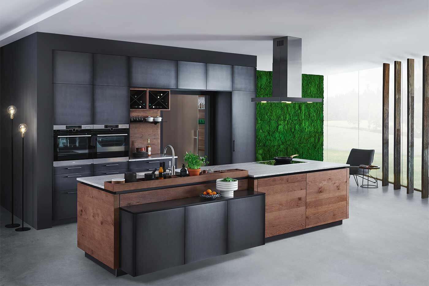 Schwarze Küche mit großen Fenstern Eine Küche mit schwarzen Schränken und einer braunen Kücheninsel. Neben der Fensterfront ist eine grüne Wand mit Mooslook