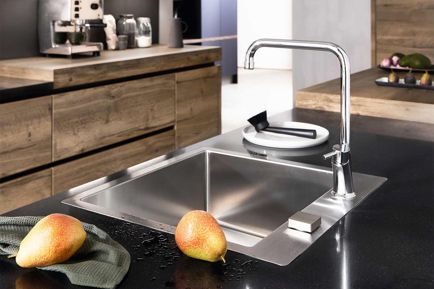 Ein Modernes waschbecken integriert in einer schwarzen Arbeitsplatte. Neben dem Waschbecken liegen Birnen