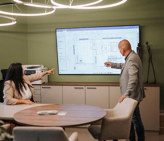 Mann und Frau zeige auf einen Fernseher, der Skizzen anzeigt