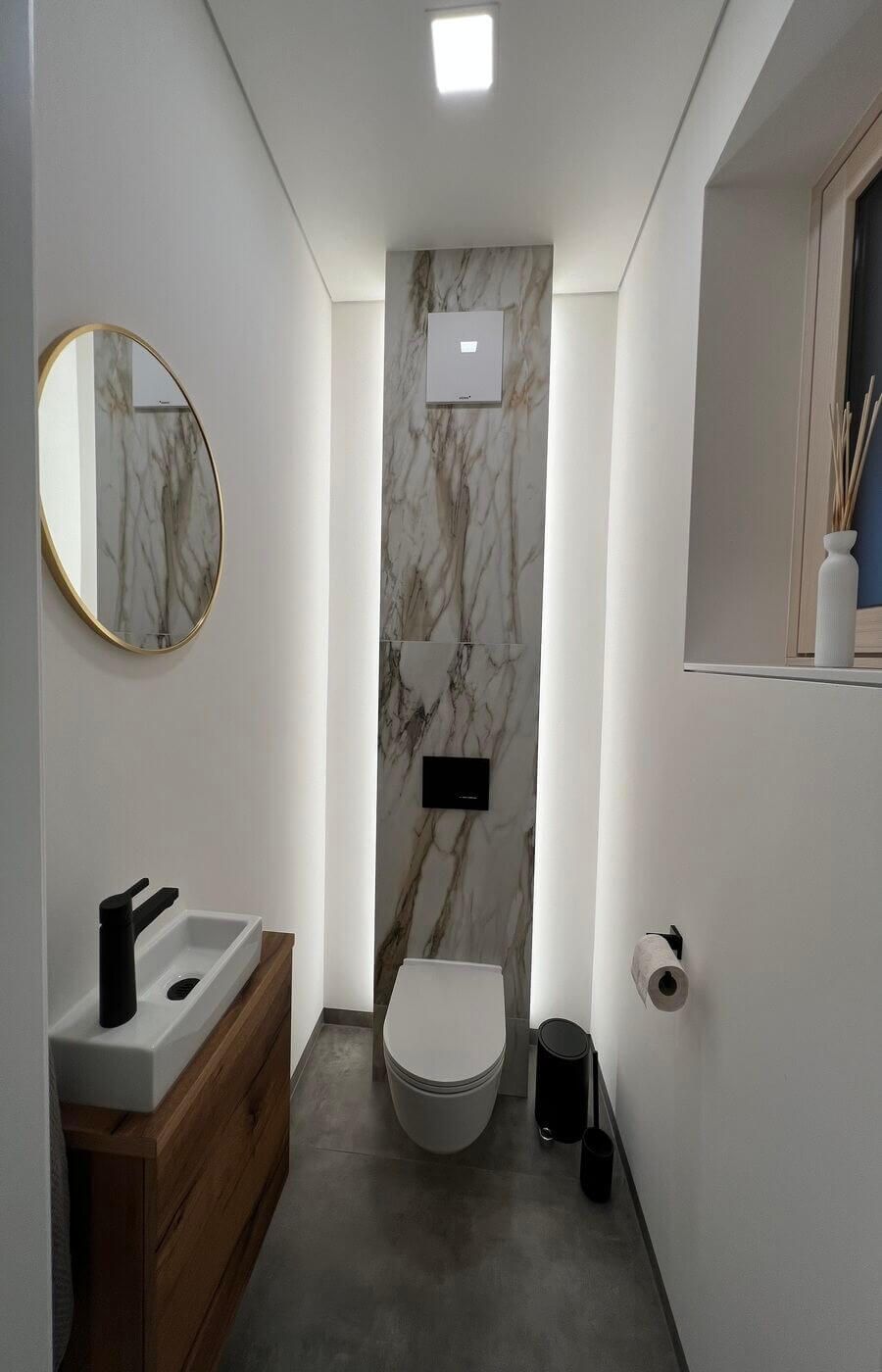 Gäste WC mit einer Toilette an einer Wand aus Marmor