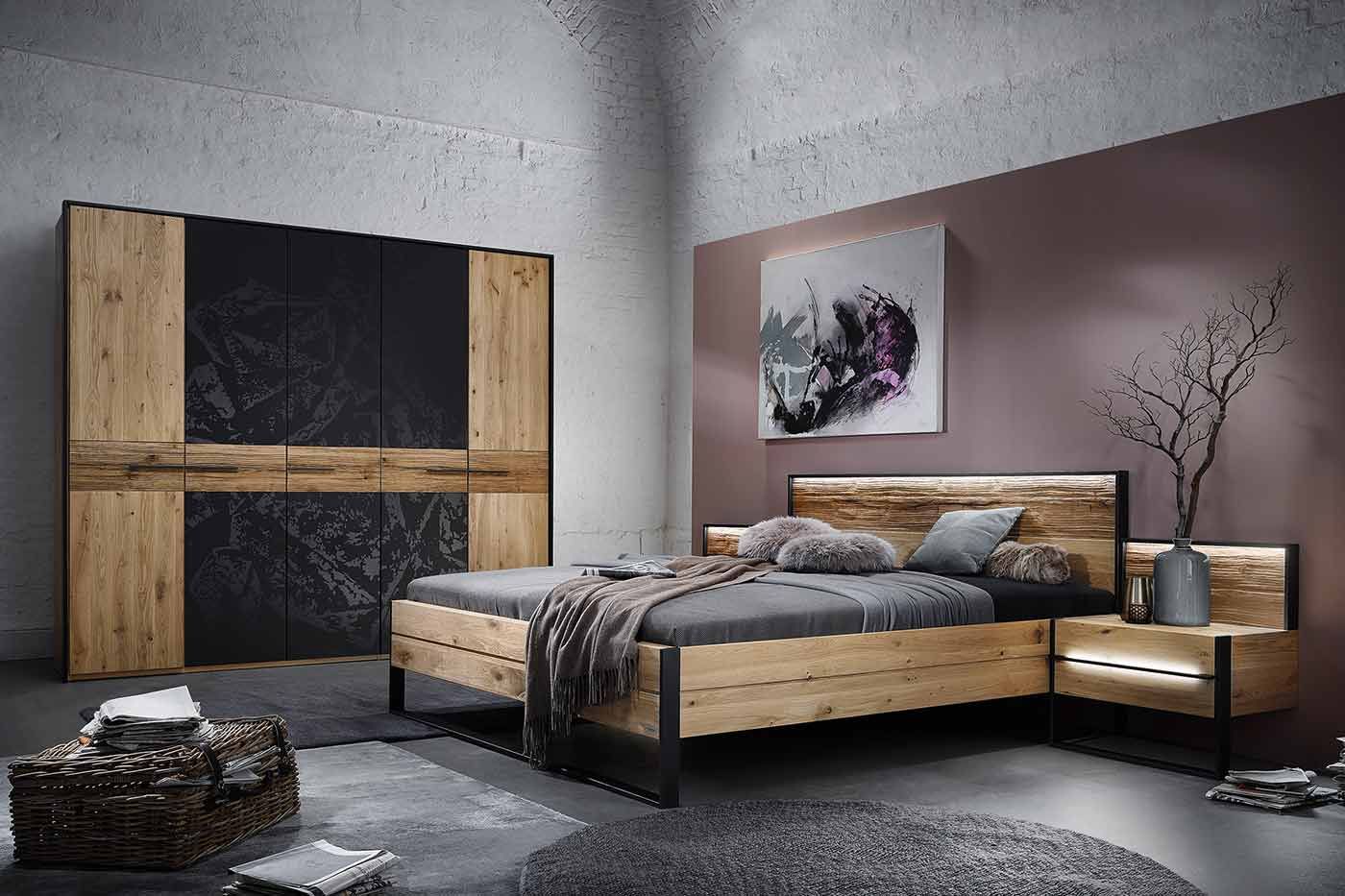 Schlafzimmer mit einem Holzbett mit dunkelgrauer Bettwäsche und einem großen Holzschrank mit schwarzen Türen