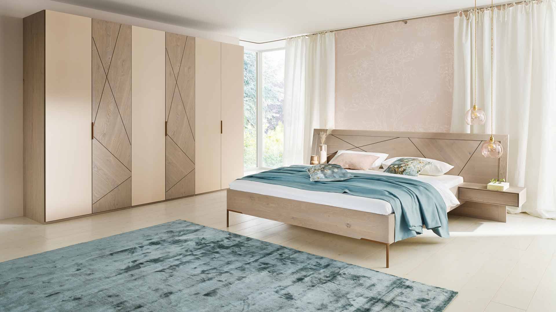 Schlafzimmer mit einem großen Schrank aus hellem Holz und cremefarbenden Elementen und ein großes Doppelbett aus dem gleichen Holz 