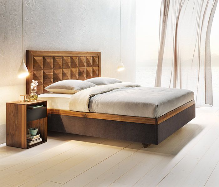 Schlafzimmer Mood 2 Holzbett mit einem geometrisch gemusterten Betthaupt und hellgrauer Bettwäsche