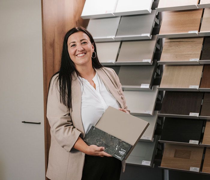 Lächelnde Frau hält Arbeitsplattenproben hoch