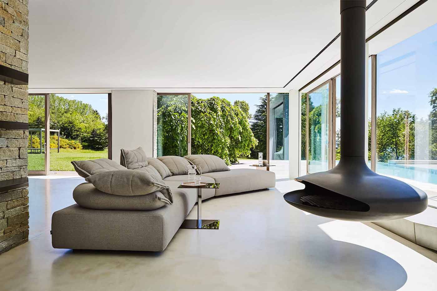 Bildergalerie Wohnzimmer Flick Flack Helles Wohnzimmer mit Fensterfronten, einem großen Sofa und einem schwebenden Kamin