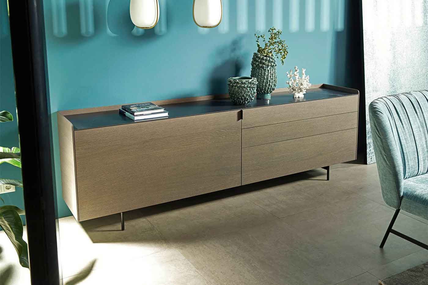 Sideboard aus Holz vor einer Wand in Petrol