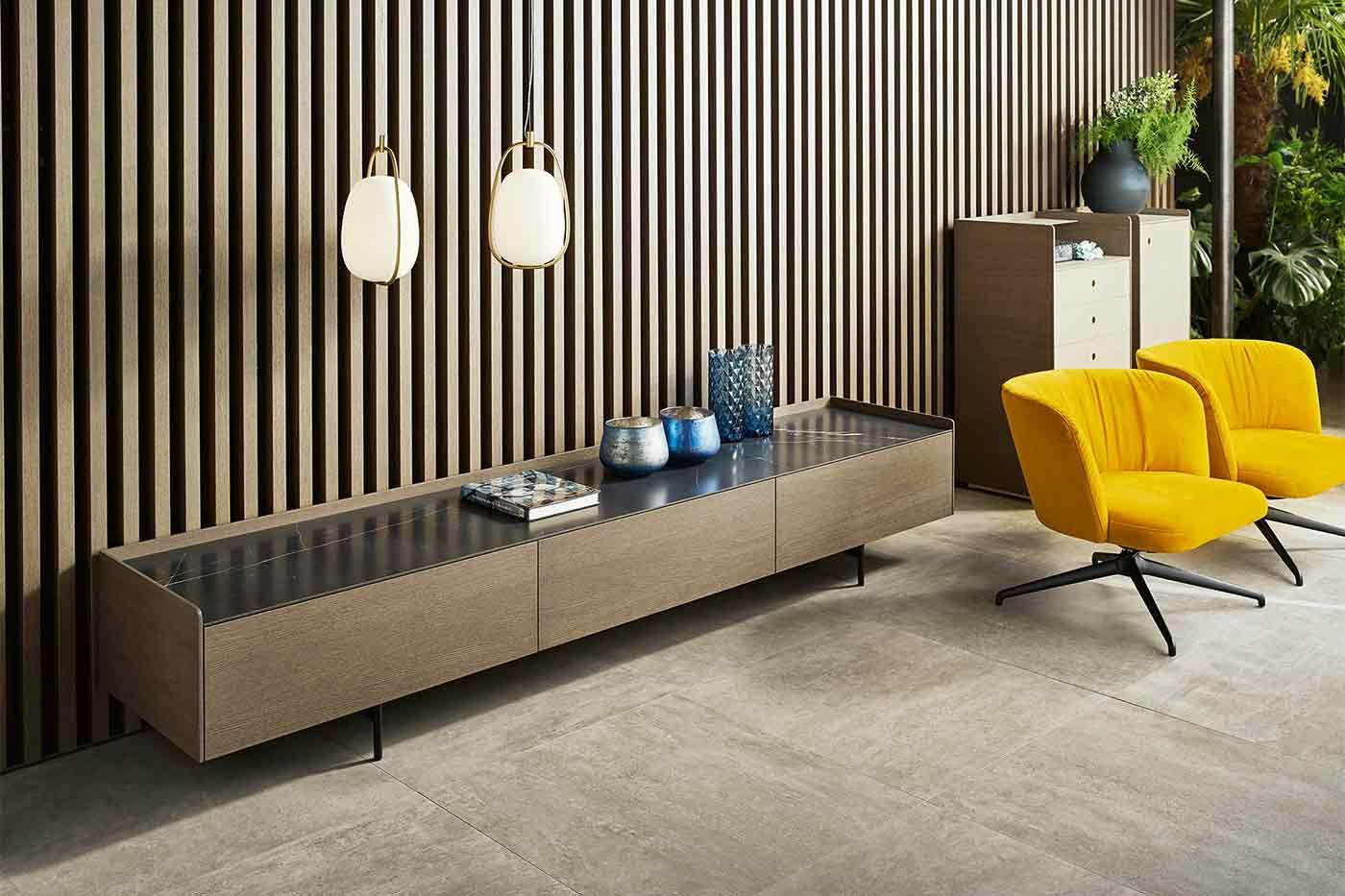 Sideboard aus dunklem Holz mit einer marmorierten Oberfläche vor einer Wand aus Holzpanellen